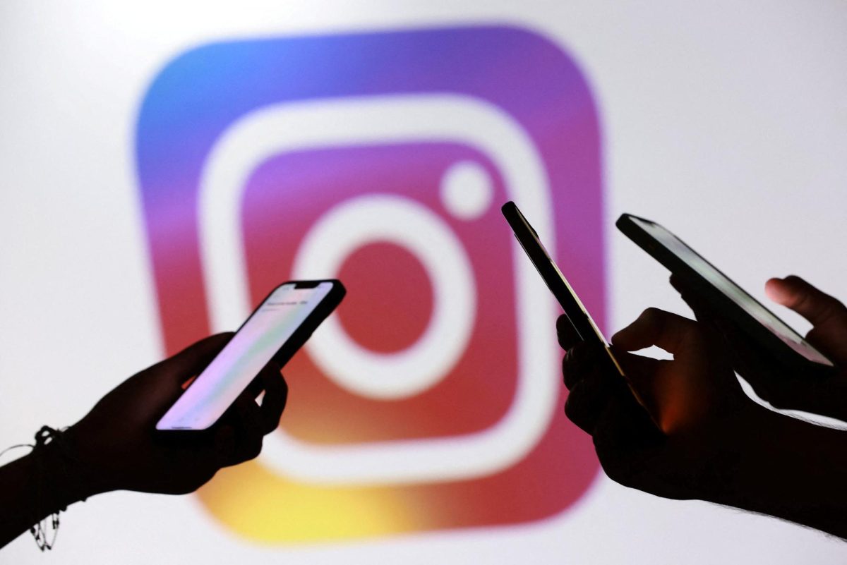 Teenagers pose for a photo while holding smartphones in front of a Facebook logo in this illustration taken September 11, 2025. REUTERS/Dado Ruvic/Illustration