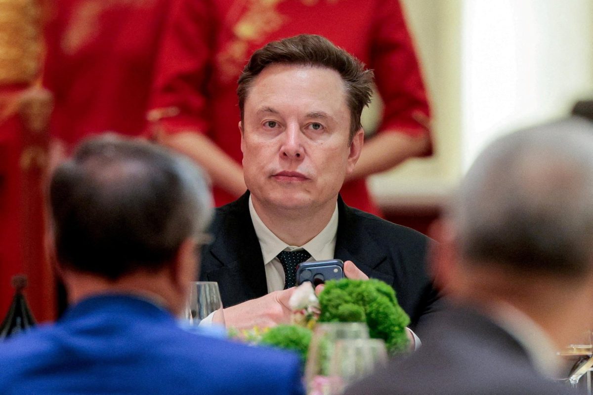 Tesla CEO Elon Musk holds a mobile phone as he arrives to attend a state banquet with U.S. President Donald Trump and Chinese President Xi Jinping at the Great Hall of the People in Beijing, China, May 14, 2026. REUTERS/Evan Vucci/